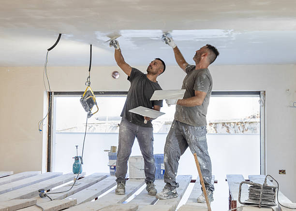 istock Two men working standing on scaffoldings, use trowel and hawk to plaster ceiling, construction 2228121079
