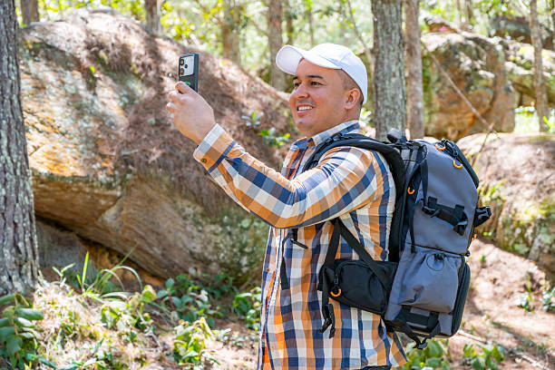 istock Smiling hiker taking a selfie in the forest with backpack 2228123055