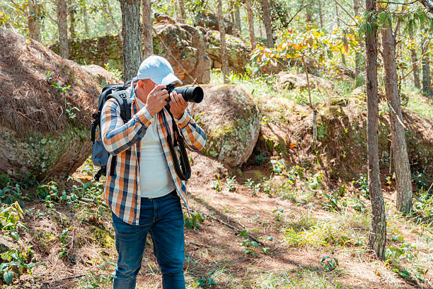 istock Photographer taking a picture in forest with camera and backpack 2228123105