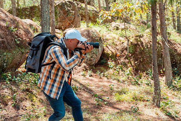 istock Photographer crouching to capture nature in forest with DSLR camera 2228123115