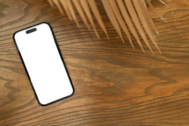istock Modern Smartphone with Blank White Screen on a Wooden Table. for showcasing mobile app designs, website layouts, or any digital content. The blank screen offers a versatile canvas for designers. 2228124224