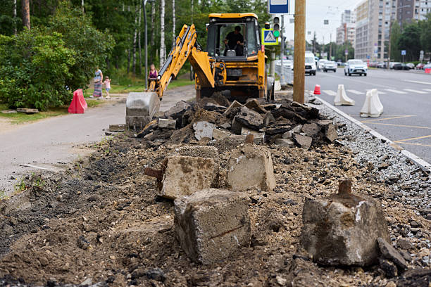 A bustling road construction scene showcasing heavy machinery, debris, and workers actively on a city street