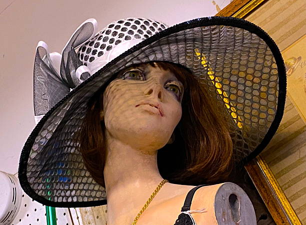 Fashion model mannequin with light Summer hat, Full brim. The mannequin's face is femine, looking to the side.