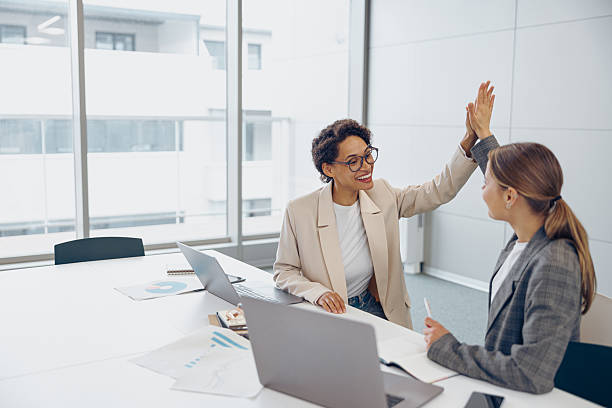 istock Successful business people giving each other a high five while working on laptop in coworking 2228132340