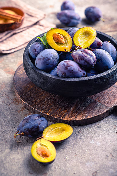 Freshly picked ripe plums (Zwetschgen) fruits in bowl with sugar and cinnamon. Prepared for baking a cake or making marmalade