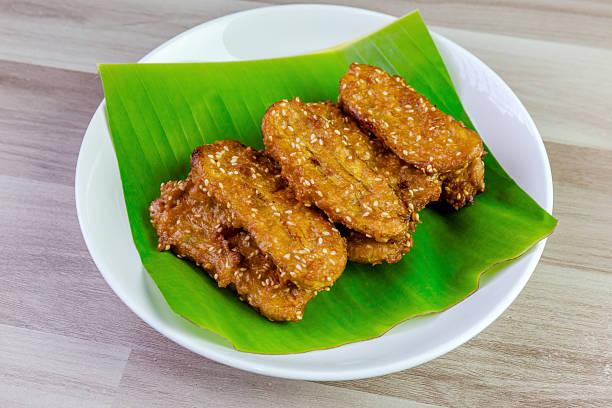 istock Crispy Thai fried bananas with sesame seeds served on a banana leaf in a white plate, Fried bananas is a traditional Asian snack with sweet, crunchy texture. Top view shot 2228135391