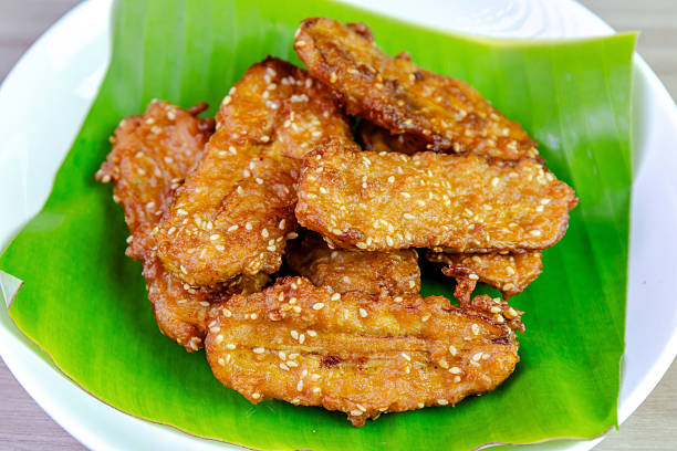 istock Crispy Thai fried bananas with sesame seeds served on a banana leaf in a white plate, Fried bananas is a traditional Asian snack with sweet, crunchy texture. Top view close-up shot 2228135396