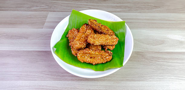 istock Crispy Thai fried bananas with sesame seeds served on a banana leaf in a white plate, Fried bananas is a traditional Asian snack with sweet, crunchy texture. Top view close-up shot, copy space 2228135399