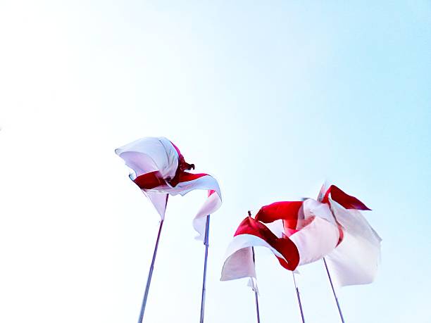 Swiss federal flag, cantonal flag of canton Aargau and municipal one of town Baden. They are waving in the wind on metal poles on the background of blue sky.