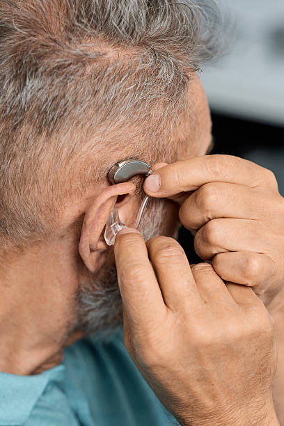 istock Grey-haired senior man with hearing impairment using hearing aid. Hearing solutions for deafness people 2228147964