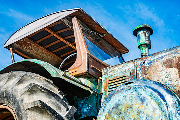 A vintage tractor sits under a bright blue sky, showcasing its rustic charm and details as sunlight reflects off its metallic surfaces.