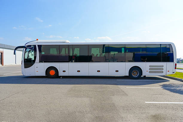 A large long tourist bus is parked, side view.