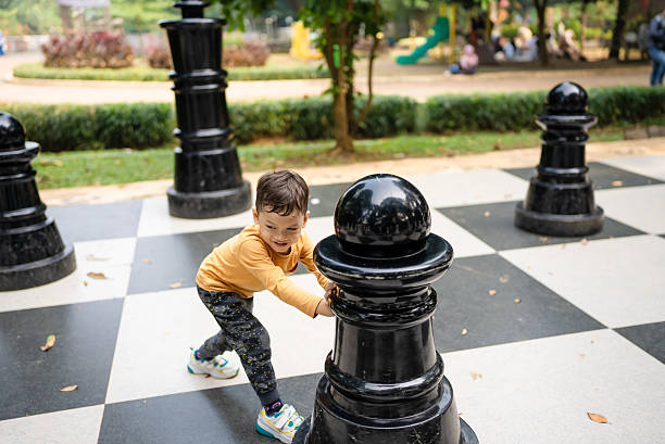 boy  playing with giant chess pieces
