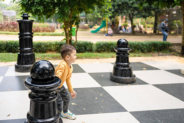 istock boy  playing with giant chess pieces 2228153842
