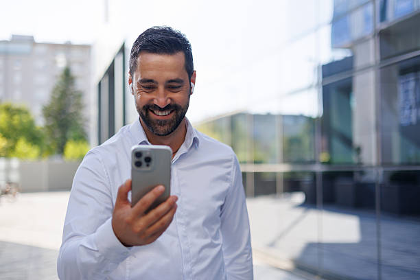istock Businessman is smiling while making a video call on his smartphone in front of an office building 2228155174