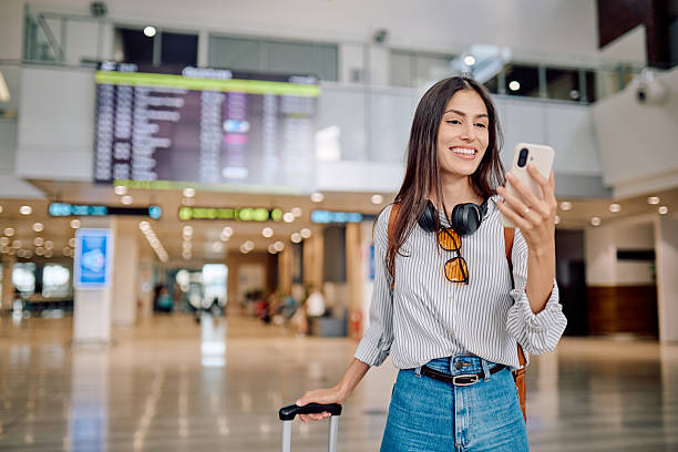 istock Young woman using mobile phone while waiting for flight at airport 2228156942