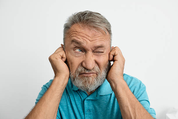 istock Elderly man touches his ear, showing frustration from hearing issues in a simple setting. Hearing loss 2228157559