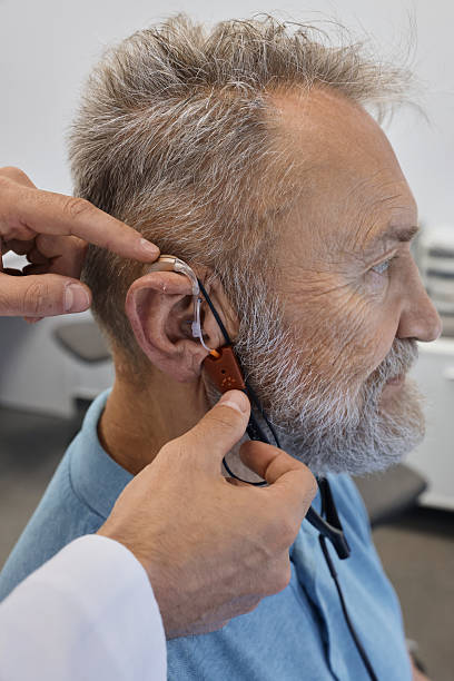 istock Hearing solutions. Audioprosthetist adjusts senior patient's hearing aids using special equipment, and takes real ear measurements 2228159421