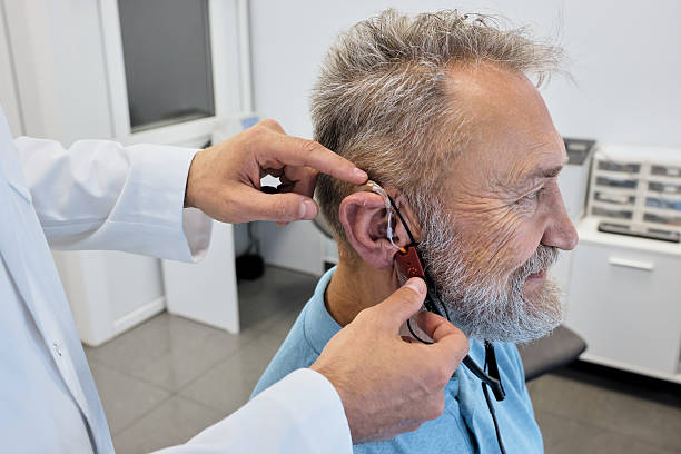 istock Audiologist carefully adjusts a hearing aid on elderly man using advanced audiological equipment for personalized fitting, side view 2228159423