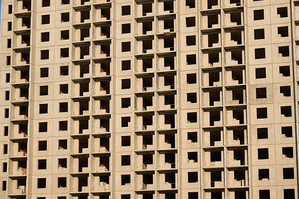 A close-up view of a concrete building wall showing repetitive window patterns and architectural structure.
