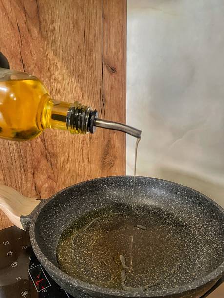Oil being poured onto an olive in white plate filled with olive oil. Close up macro studio shot.