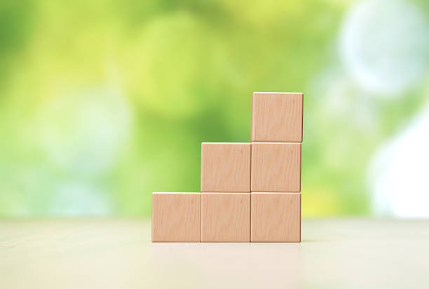 istock Stacked Wooden Blocks on Light Background With Blurred Greenery During Daylight 2228161520