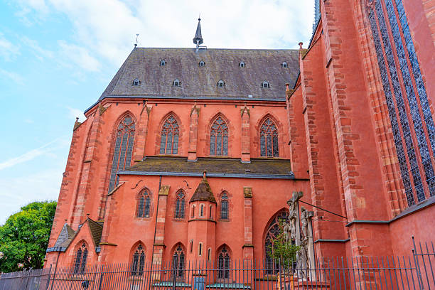 Frankfurt, Germany - June 10, 2025: Architectural features of Frankfurt Cathedral displayed, highlighting the Gothic style, intricate stonework, and vibrant red exterior under a clear blue sky.