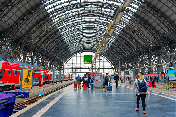 Frankfurt, Germany - June 10, 2025: Interior view of Frankfurt Main Train Station featuring passengers, red trains, and a steel and glass structure, captured during the day.
