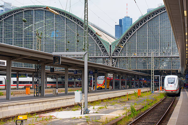Frankfurt, Germany - June 10, 2025: Architectural details of Frankfurt's historic train station with modern trains, steel structures, and glass elements under a cloudy sky.