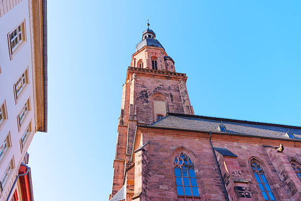 Low angle view of a beautifully detailed historic building in Heidelberg, Germany, showcasing intricate architectural elements with a bright blue sky backdrop.