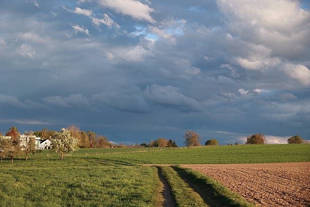Cloudy sky with a house in the distance. The sky is overcast and the grass is green