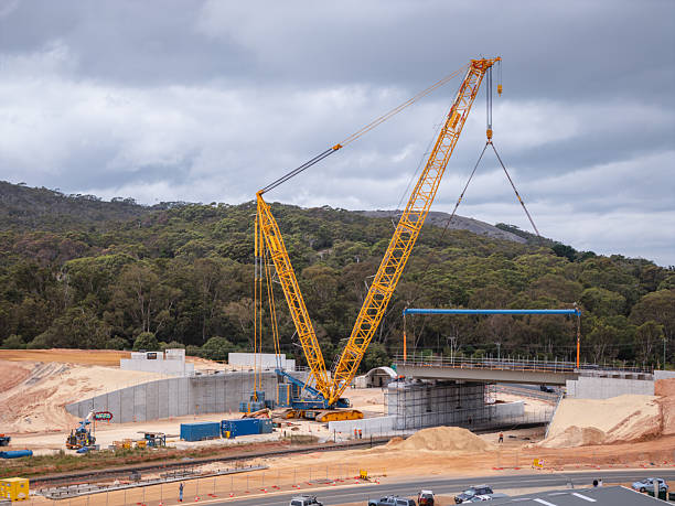 istock Yellow Construction Crane Positioning Bridge at Highway Construction Site 2228167907