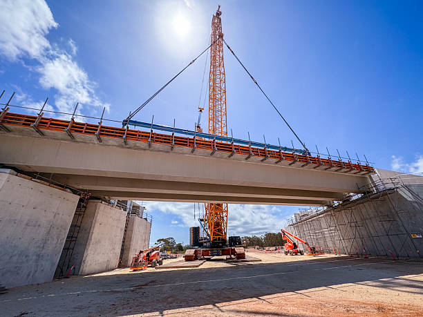 istock Large Crane Hoisting Bridge Segment at Construction Site Under Bright Sunny Sky 2228168474