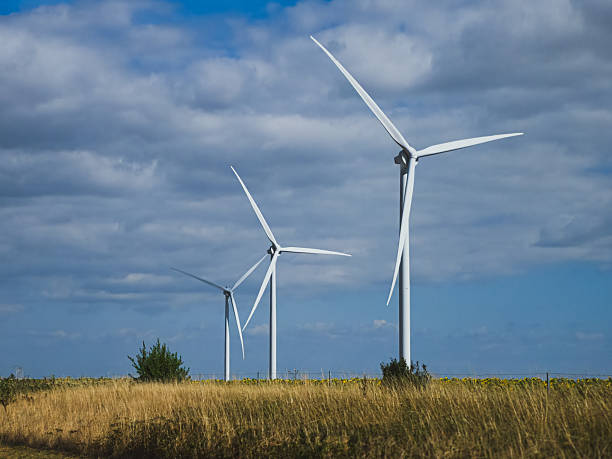 istock Wind turbines on grassy field under partly cloudy sky, 2228168857