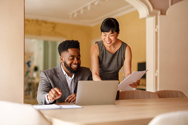 istock Smiling business professionals with documents and laptop discussing project at desk in modern office 2228169410