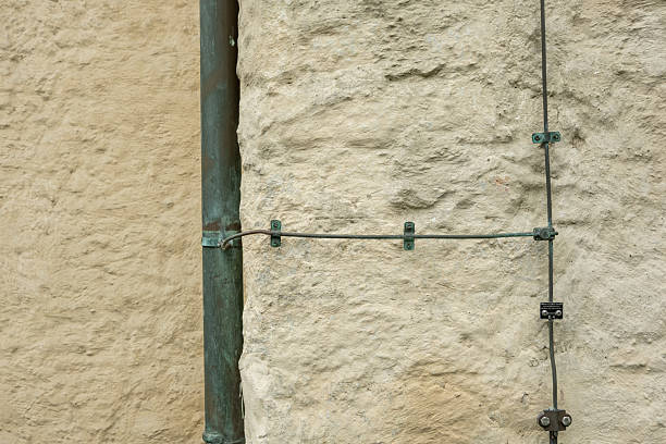 Copper downspout and electrical wiring create an interesting juxtaposition on a textured wall