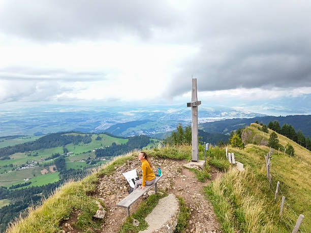 active couple rests on a mountain peak looking on a mountain landscape