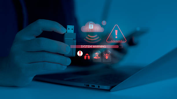 istock Close-up of a hand plugging a USB with digital system warning and malware alert icons. Concept of cybersecurity breach, data threat, and computer virus detection. 2228174783