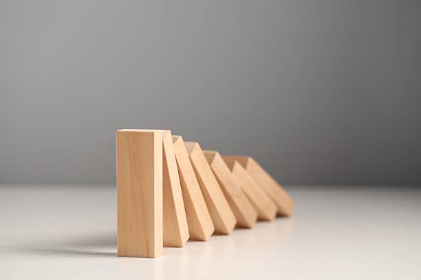 istock Domino effect. Wooden blocks falling on white table, closeup 2228176175