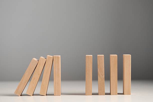 Domino effect. Wooden blocks falling on white table