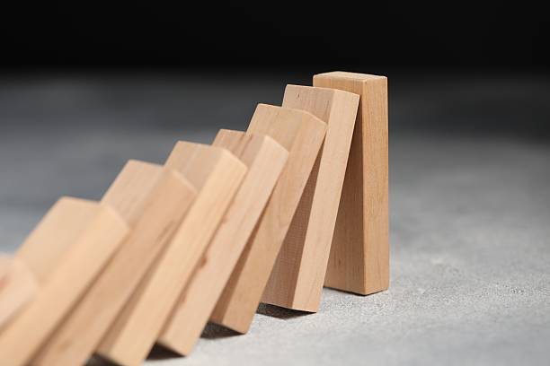 istock Domino effect. Wooden blocks falling on grey table, closeup 2228176182