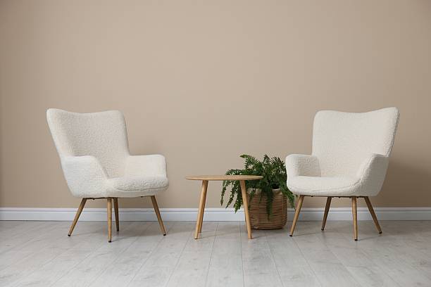 istock Soft armchairs and coffee table near beige wall indoors 2228177041