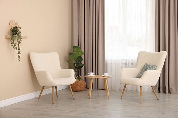 Soft armchairs and coffee table near beige wall indoors