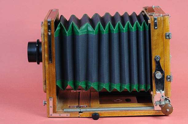 Vintage large format wooden camera on a pink background.
