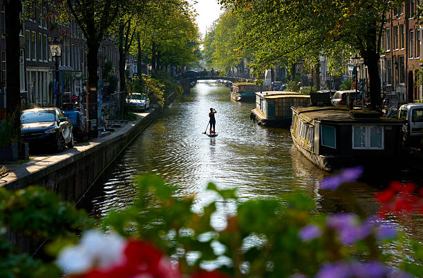 A paddleboard cruise on quiet Egelantiersgracht canal in downtown Amsterdam, Netherlands. September 18, 2024.