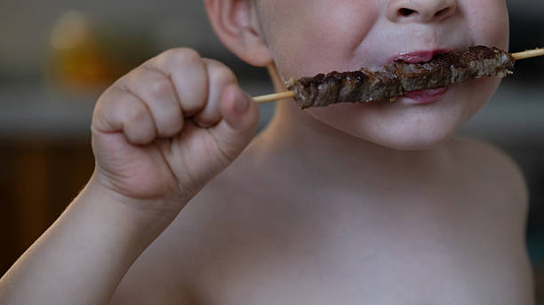 istock Child biting grilled meat skewer with hands 2228191264