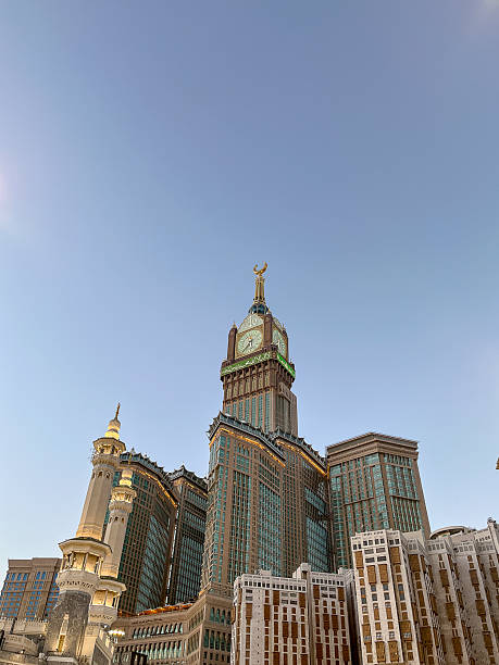 The iconic Abraj Al-Bait Clock Tower stands tall under a clear blue sky in Mecca, Saudi Arabia. A prominent landmark near the Grand Mosque, the tower is one of the tallest buildings in the world.
