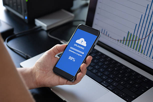 istock Woman uploading files to cloud using her smart phone 2228195038