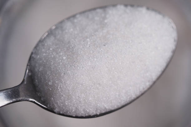 istock Close-up of white sugar on spoon in kitchen setting 2228195130