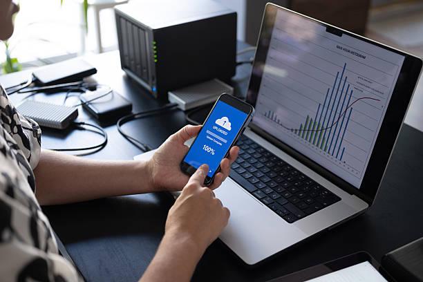 istock Woman uploading files to cloud using her smart phone 2228195155
